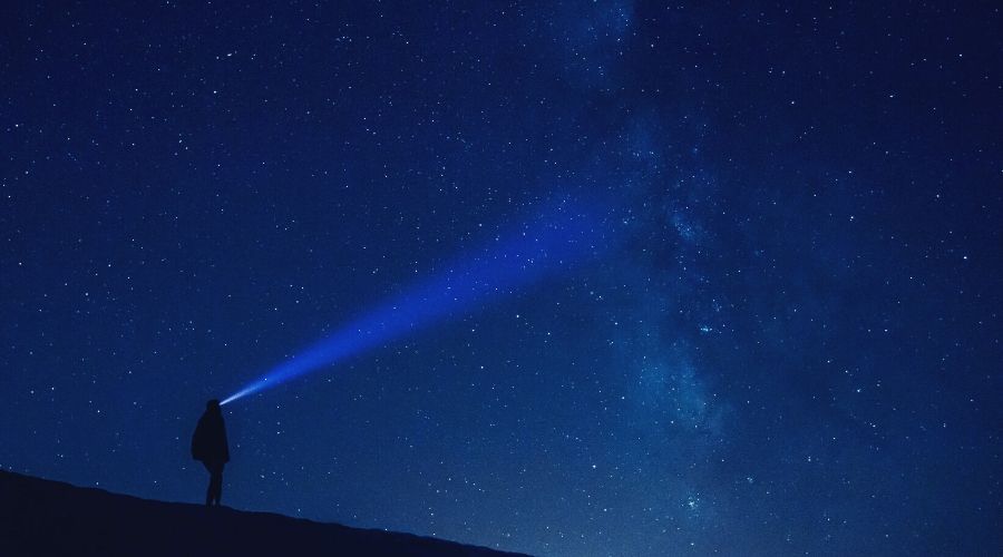 hiker staring into dark sky with headlamp intext