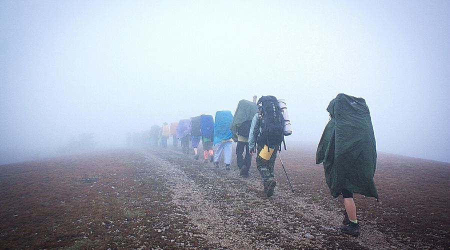 hikers in rain gear walking in mist - In Text