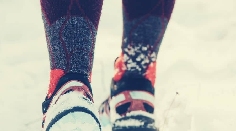 closeup of hiker wearing long socks and boots in snow