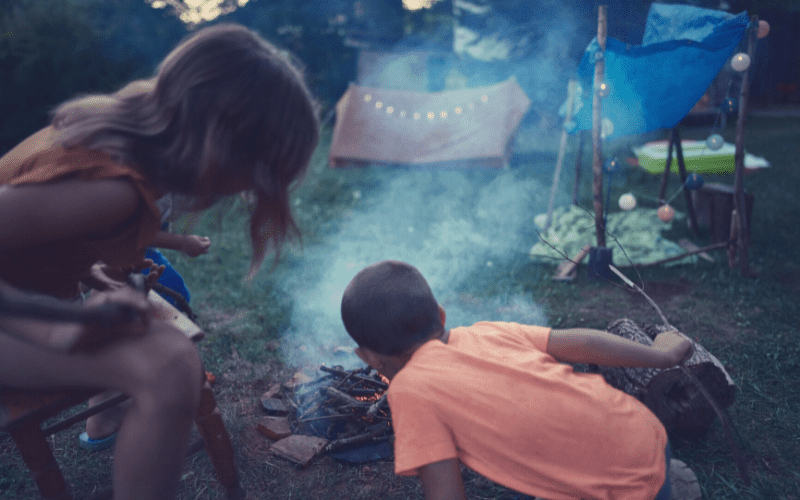 Kids at a campsite building a fire