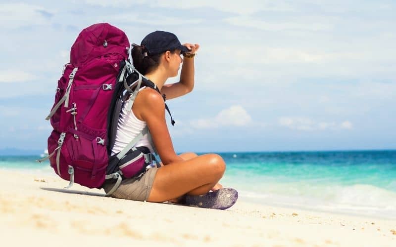 Backpacker with backpack with padded hip belt on sitting on the beach