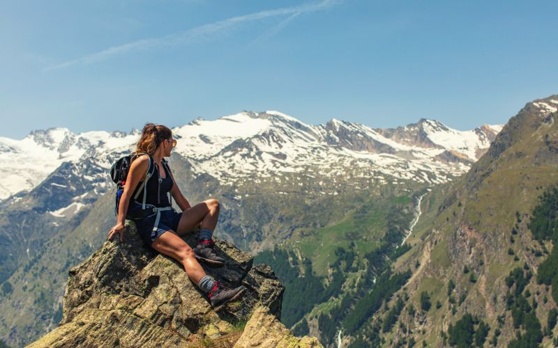 Woman hiker sitting on rock looking at mountains