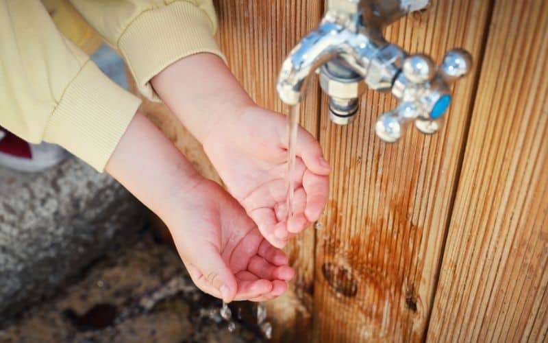Kid washing hands at a campsite outdoor tap